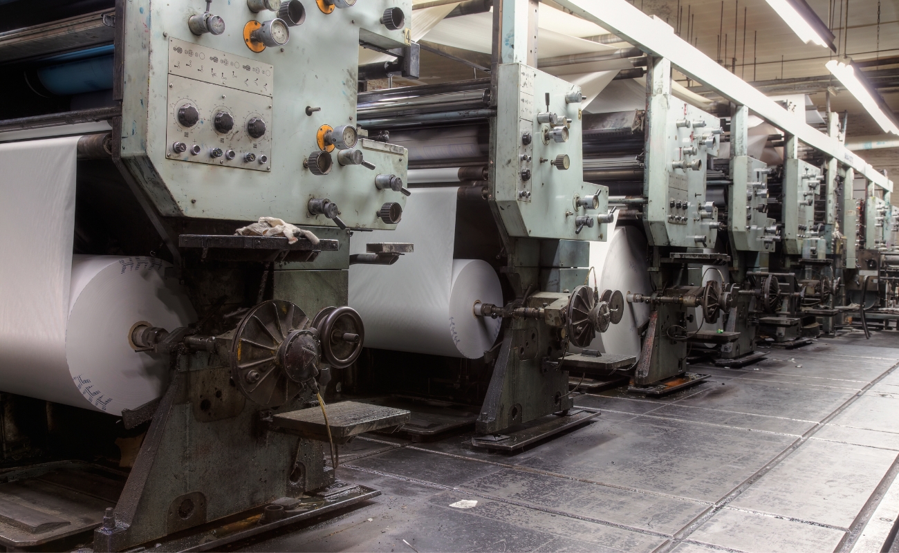 Commercial printing presses in a manufacturing facility representing production-biased managed services and marketing execution.