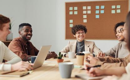 Diverse business team collaborating during a strategy meeting in a modern corporate office with laptops, coffee, and brainstorming tools. 