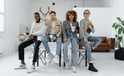Four creative professionals collaborating in a modern office, representing Continuum’s hybrid onshore and offshore creative services model focused on cost efficiency, quality, and speed. 