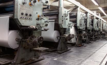 Commercial printing presses in a manufacturing facility representing production-biased managed services and marketing execution.