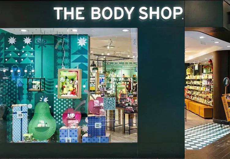 The Body Shop storefront with a holiday-themed window display and beauty products visible inside.