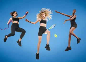 Three women in athletic wear jumping against a blue background, demonstrating fitness, dance, and tennis movements.